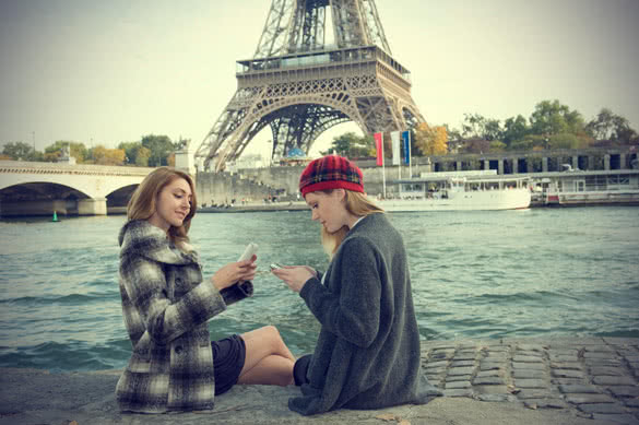 young women texting near seine river