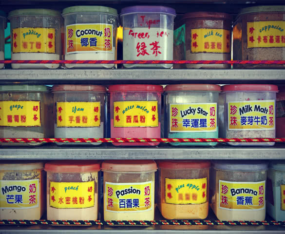 Rows of colorful container containing food extract flavoring powder on the shelf of a Chinese street stall