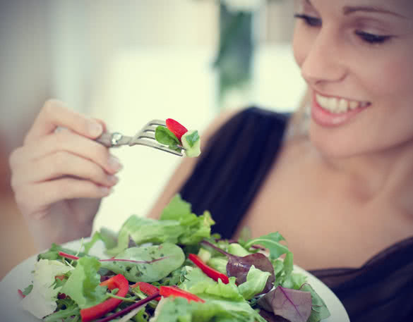 Woman eating delicious green salad