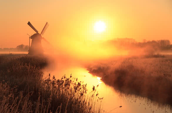 dutch sunrise with traditional windmill and a canal