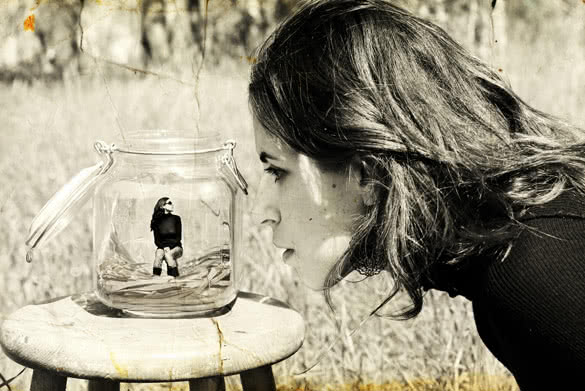 girl looks at herself in the glass jar