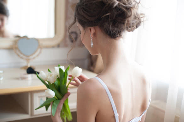 young beautiful woman with bouquet of white tulips in front of mirror