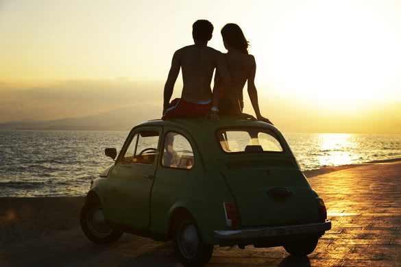 couple at sundown on the beach with car