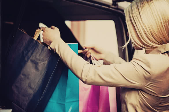 blonde woman putting shopping bags in car