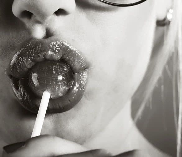 Young beautiful woman with lollipop in her mouth closeup