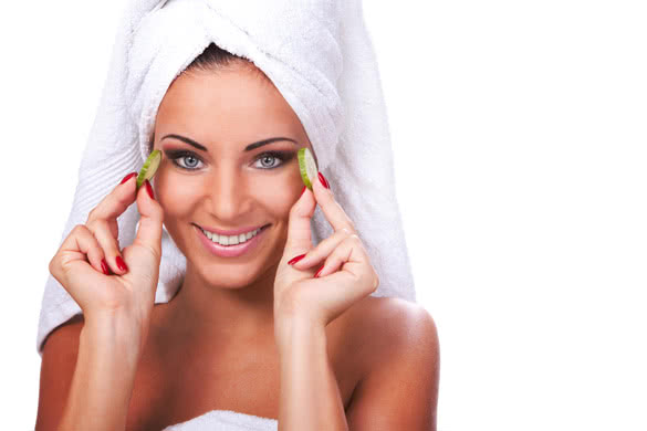 Happy girl in towel holding cucumber slices