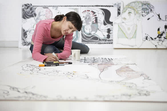 Young female artist drawing on large paper at home office
