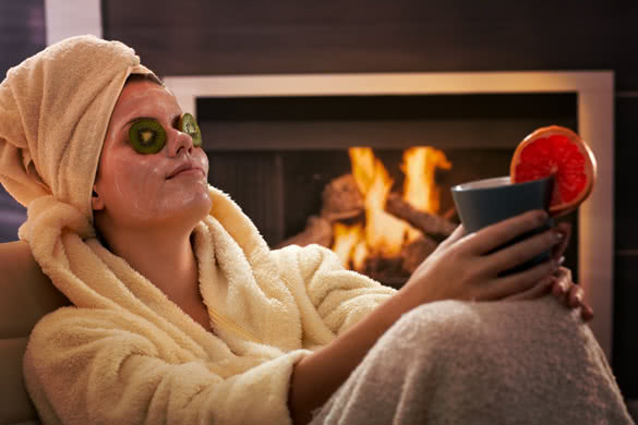 Woman in bathrobe and towel relaxing in facial mask