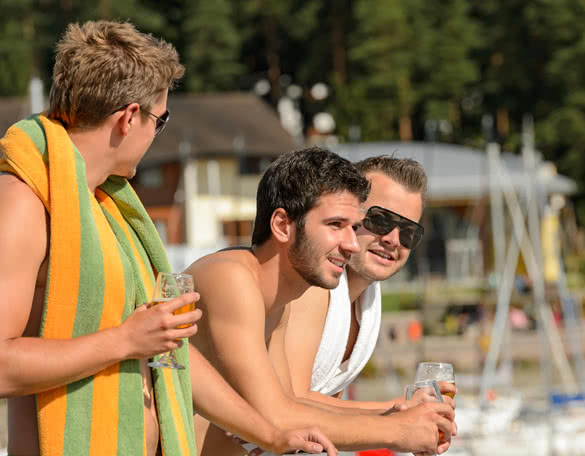 Young guys holding glasses talking at beach