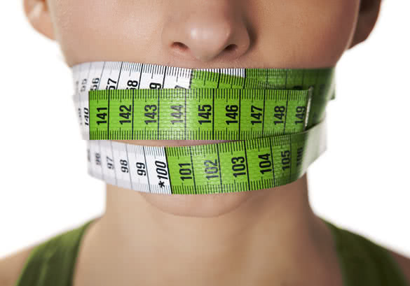 young woman with a green measuring tape covering the mouth