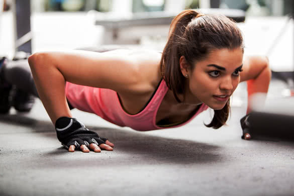 Beautiful Latin woman doing push ups in the gym