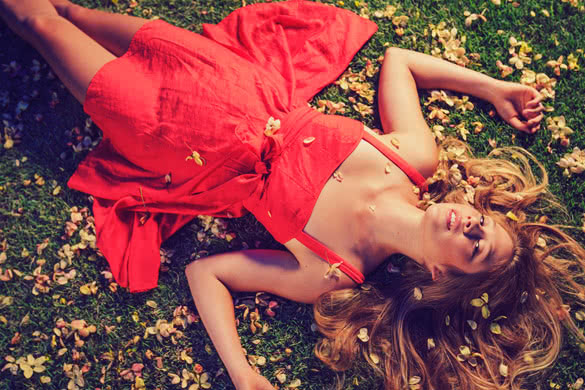 Beautiful Young Woman Lying on Grass with Flowers