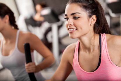 Pretty Latin young women working out in an elliptical trainer in a gym