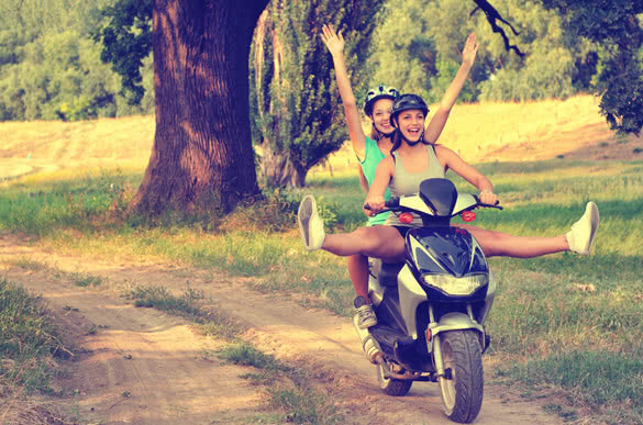 Two teenage girls riding motorcycle on the countryside