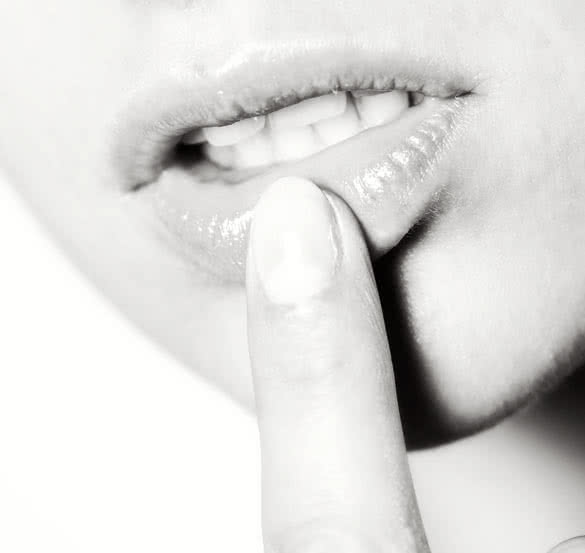 Macro of young model touching lips with finger