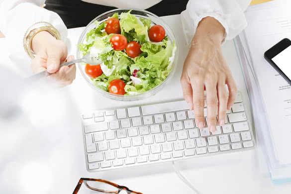 Young businesswoman eating a salad while working in office