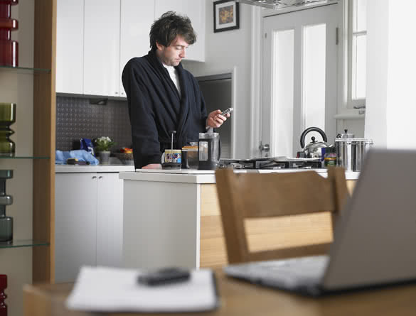 Young man text messaging at kitchen