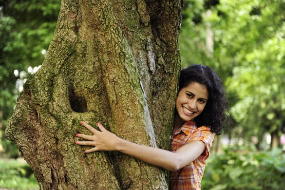 happy woman hugging a tree in the forest