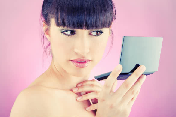 woman holding a black mirror and looking at it