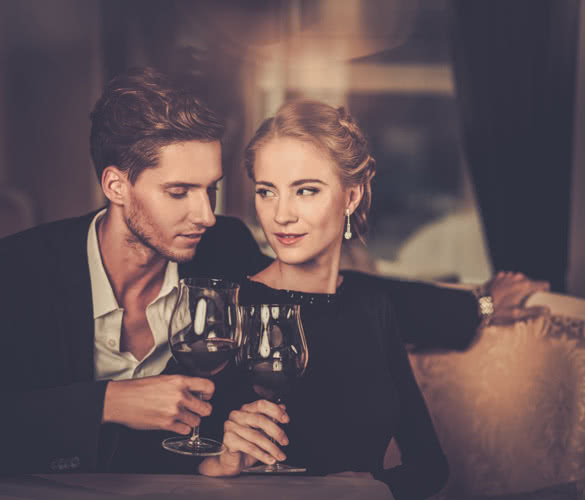 Beautiful young couple with glasses of wine in luxury interior