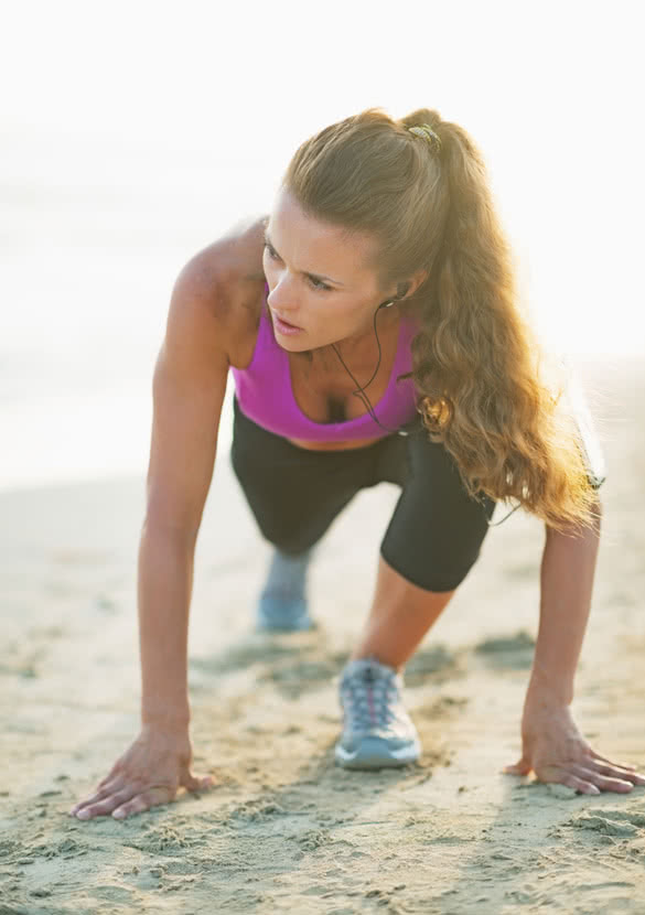 Fitness young woman stretching on beach