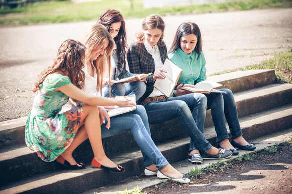 Group of students sitting with a books on street