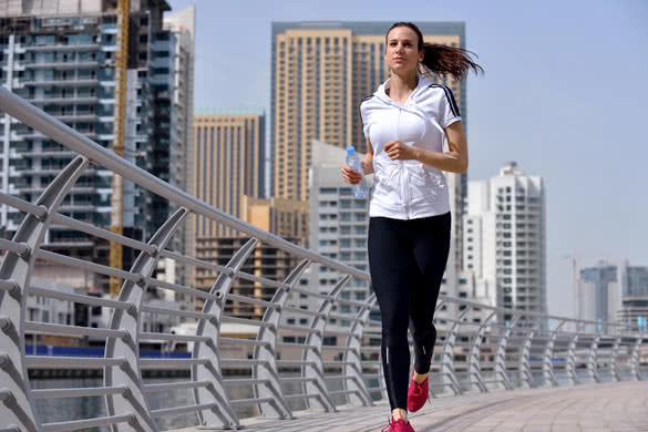 Woman runner outside jogging at morning with Dubai urban scene in background