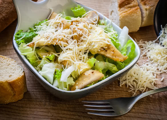 fresh caesar salad on bowl with parmesan cheese