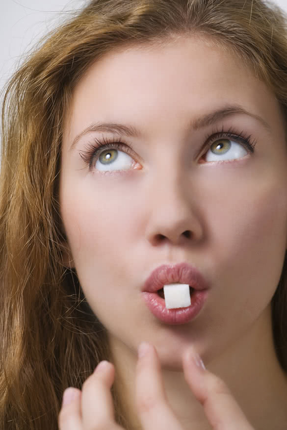 woman holding a sugar cube between her teeth in her mouth