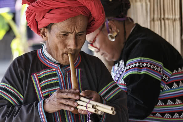 Karen man in traditional costumes playing a flute