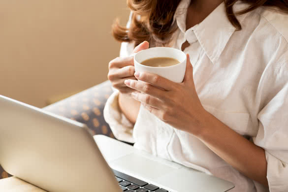 Woman drinking coffee and using digital tablet in the morning