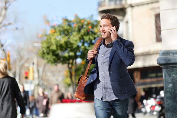 Young urban businessman on smart phone running in street