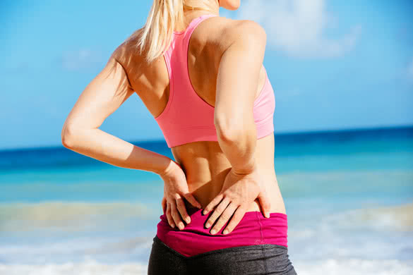 Athletic fitness woman rubbing the muscles of her lower back