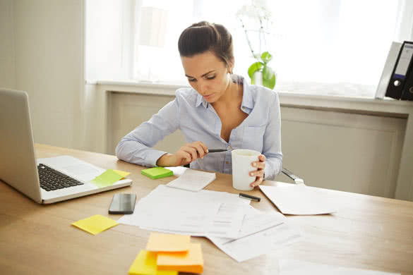 Attractive young woman working at the desk with sticky notes and laptop