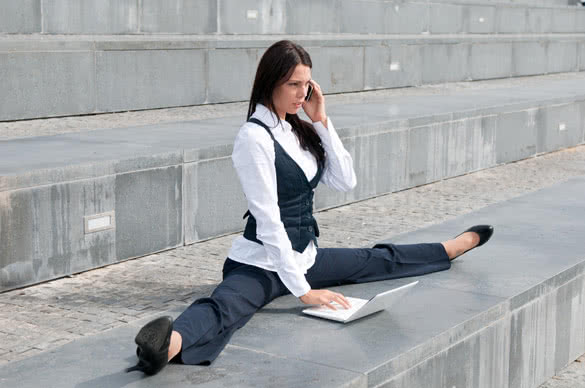 Young business woman in gymnastics pose working with computer and calling mobile phone