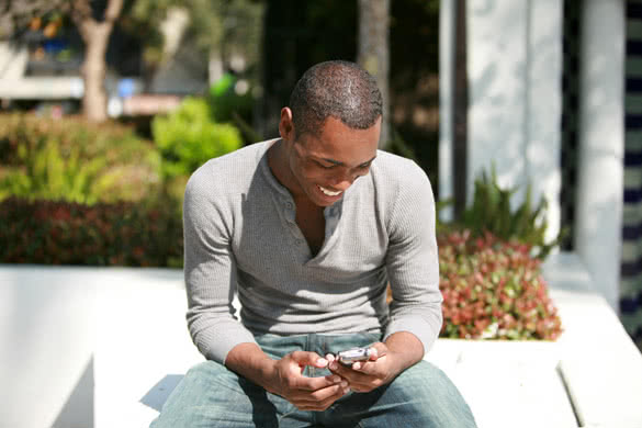 young black guy reads text message on his phone