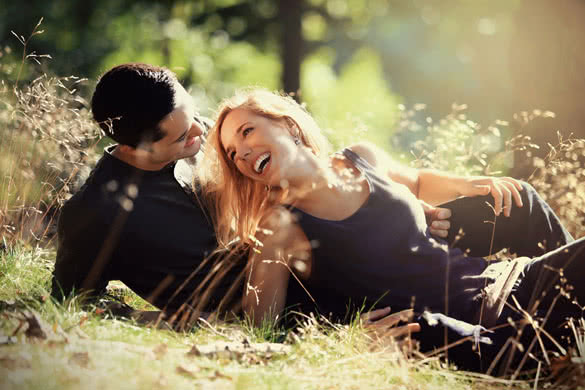 young couple smiling at each other during a romantic date in the forest