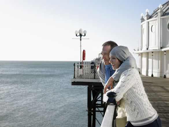 Couple standing on pier looking out at sea