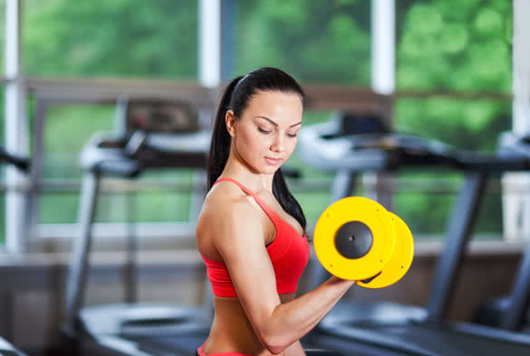 Woman in gym sport exercising with dumbbells lifting weights