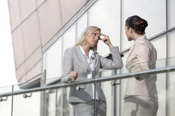 Young businesswoman arguing with female colleague at office railing