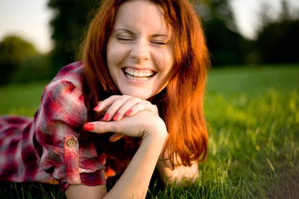 Young happy woman relaxing on green grass
