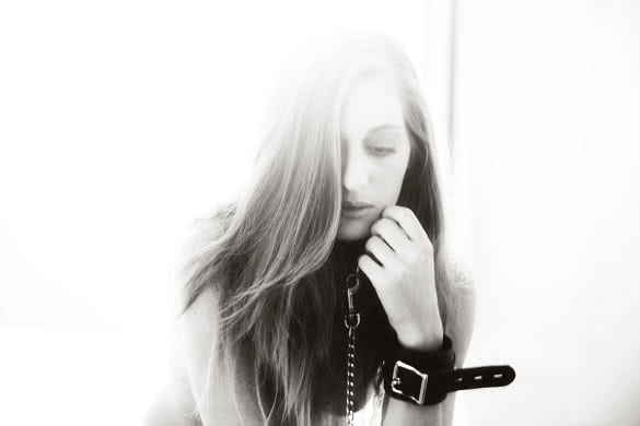 Beautiful young woman wearing BDSM cuffs and leash