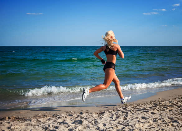 Female runner jogging during outdoor workout on beach