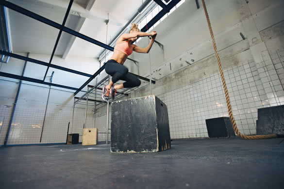 Low angle view of young female athlete box jumping at a crossfit gym