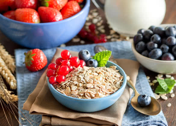 Rolled oats in a blue bowl on a napkin with berries