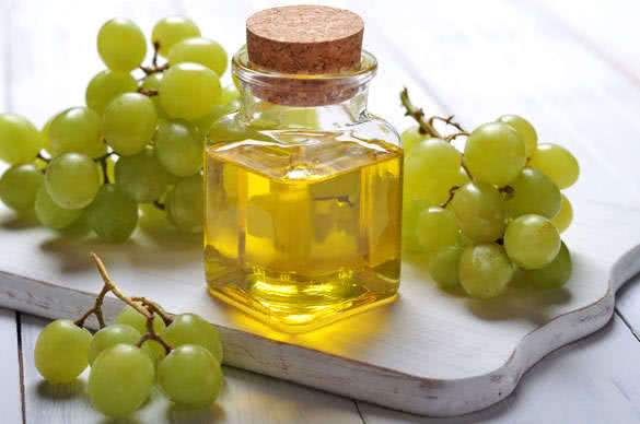 Grape seed oil in a glass jar on wooden background