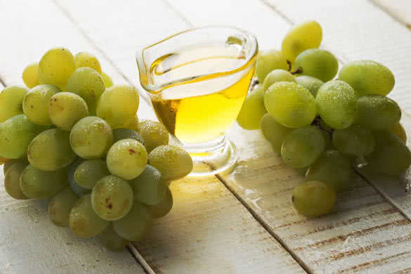 Grape seed oil on white wooden background