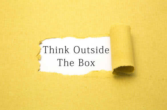 Think outside the box text on torn brown paper