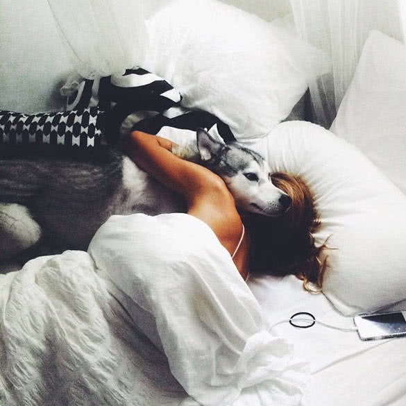 woman lying in her bed with her dog