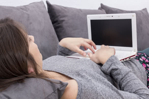 Girl-using-laptop-lying-on-sofa